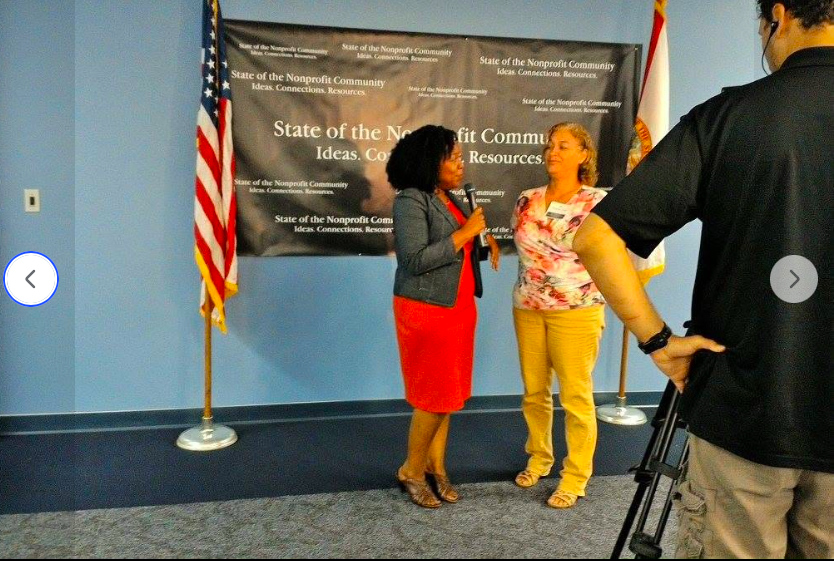 Aretha Simons being interviewed in front of the SONC banner